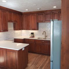 an empty kitchen with wooden cabinets and white counter tops, including a refrigerator freezer