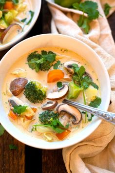 two bowls of soup with broccoli, carrots and mushrooms