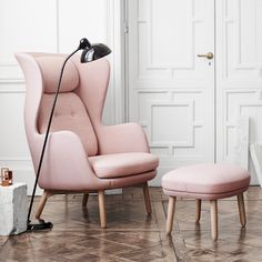 a pink chair and footstool in front of a white door