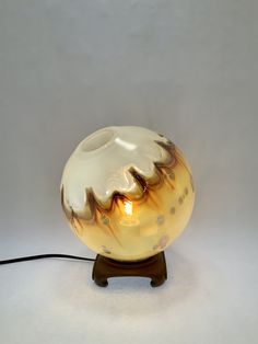 a lamp that is sitting on top of a wooden stand with a light in it