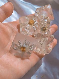 two pieces of clear glass with flowers on them in someone's hand, one being held by the other