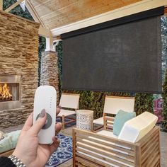 a person holding a remote control in front of a fire place with chairs and couches