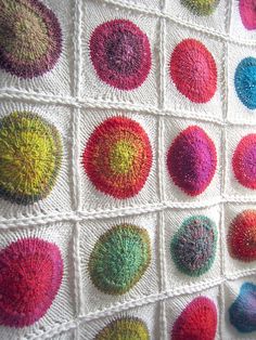 a crocheted wall hanging with many different colored balls on it's side