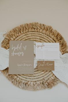 the wedding stationery is laid out on a woven mat