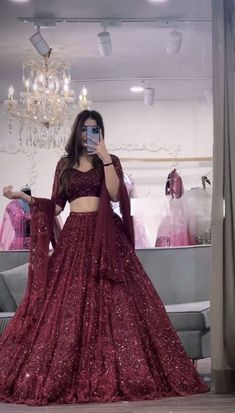 a woman taking a selfie while wearing a red gown and matching cropped top