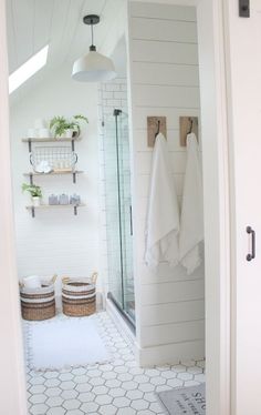 a bathroom with white walls and hexagonal tile flooring in the shower area