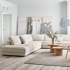 a living room with white furniture and wood flooring