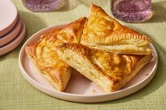 three pieces of pie on a plate next to pink plates and cups with saucers