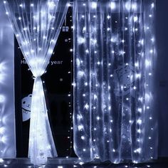 the curtains are covered with white lights in front of a black wall and window sill