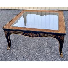 an antique coffee table with glass top and gold trimmings on the legs,