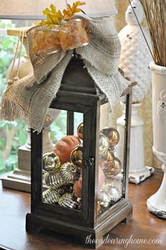 a lantern with a bow on it sitting on top of a table next to a window