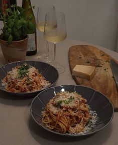 two plates of spaghetti with parmesan cheese and wine