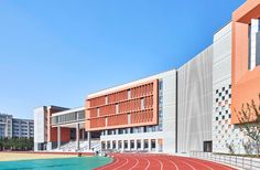 an outdoor track in front of a building with red and white tiles on the side