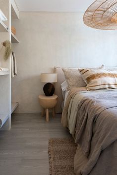 a bed sitting next to a lamp on top of a wooden table in a bedroom