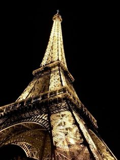 the eiffel tower lit up at night with lights on it's sides