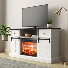 an entertainment center with a flat screen tv on top of it and a fire in the fireplace