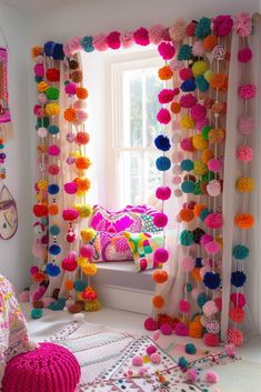 colorful pom - poms are hanging from the window sill in this bedroom