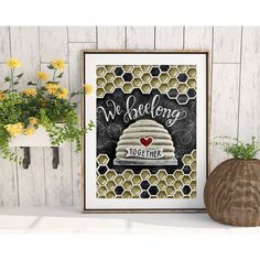 a framed print with the words we belong together on it next to some potted plants