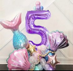 the number five is made out of balloons and mermaid tailes, as well as seashells