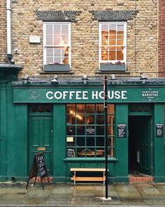 a green coffee house sitting on the side of a street