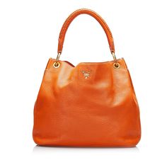 This hobo bag was made from orange leather. It features an open top with magnetic snap closure. The gold-tone details give the Bag touch of elegance. It is carried on the shoulder by the rolled/braided leather handle. The interior features a zippered side compartment. Prada Hobo Bag, Prada Hobo, Miuccia Prada, Orange Bag, Orange Leather, Braided Leather, Bag Bag, Louis Vuitton Bags, Fashion Labels