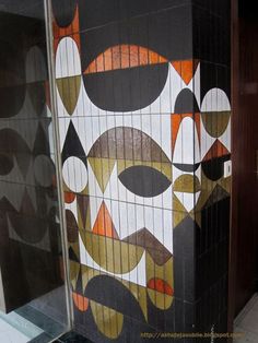 a tiled wall with an abstract painting on it's side next to a door