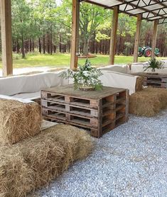 hay bales are stacked on top of wooden pallets under a covered patio area