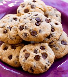 chocolate chip cookies are piled on top of each other in a purple plate, ready to be eaten