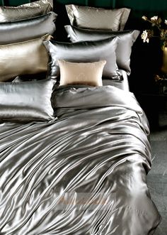 a bed covered in silver sheets and pillows