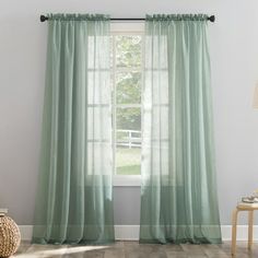 a living room with a large window covered in green curtains and a wooden table next to it