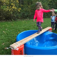 two children playing in a water play area with an above ground pool and wooden bridge