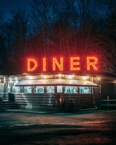 a diner is lit up at night with the word dinner on it's roof