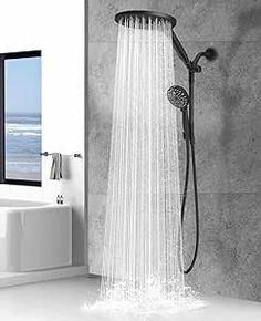 an open shower head with the water running down it's side in front of a window