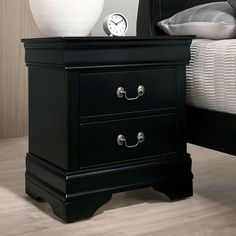 a black night stand with two drawers and a clock on the top of it in front of a bed