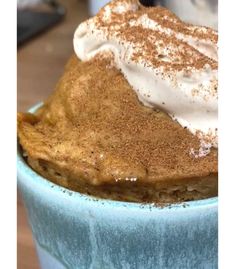 a dessert in a blue bowl topped with whipped cream and cinnamon on top, sitting on a table