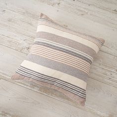 a striped pillow sitting on top of a wooden floor next to a white wall and wood floor