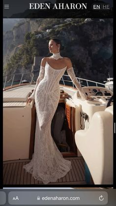 a woman in a white dress standing on the deck of a boat