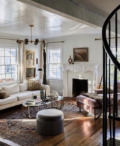 a living room filled with furniture and a fire place next to a stair case in front of a window