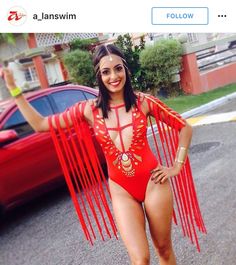 a woman in a red bodysuit standing next to a car