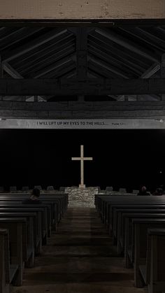 the inside of a church with pews and a cross on the wall above it