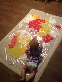 a baby is sitting on the floor with some paint