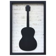 an acoustic guitar is mounted in a black frame