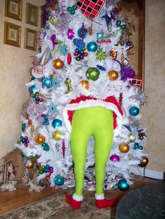 a white christmas tree with green pants and ornaments on it's bottom, in a living room