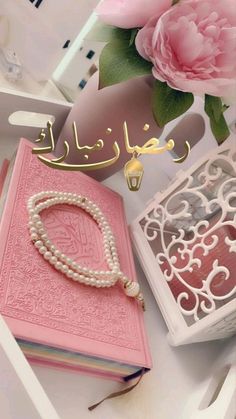 there is a pink book with pearls on it and flowers in the corner next to it