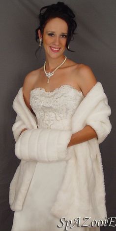 a woman in a white dress and fur coat posing for the camera with her arms crossed