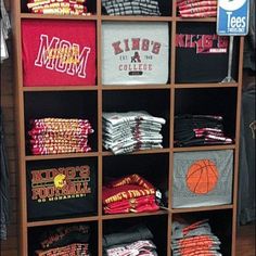 a wooden shelf filled with t - shirts and other sports apparel on top of it