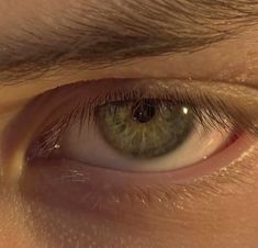 an extreme close up shot of the green eye of a young man looking into the camera