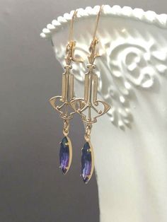 I love the glamorous jewelry worn by flappers in the Roaring Twenties. These 1920s inspired earrings feature Art Deco style brass connectors and vintage purple faceted glass beads. The brass connectors are lightweight yet study. They are textured on the front and hollow on the back. (SEE 2nd PHOTO) The earrings measure 2 1/2 inches long and hang from brass leverback ear wires. Style: ZELDA See more Art Deco inspired jewelry in my shop: http://BohemeBijou.etsy.com Flapper Jewelry, Purple Art Deco, Art Deco Jewelry 1920s, Art Deco Inspired Jewelry, 1920s Jewelry, Glamorous Jewelry, Deco Earrings, Purple Art, Roaring Twenties