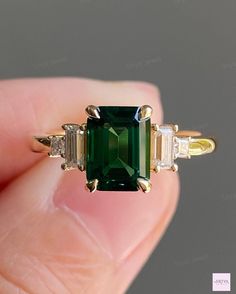 an emerald ring with three baguets on the side