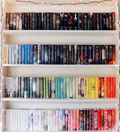 a book shelf filled with lots of books under a christmas light covered in fairy lights